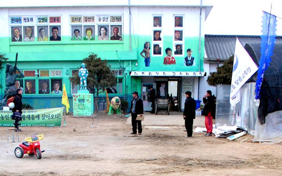 Several men mill about inside the barricaded grounds of the Daechu-ri Elementary School on Tuesday.