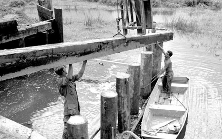 Seabees fit together the pieces of the 210-by-24-foot timber bridge across a river on Route 1 between Phu Loc and Lang Co, South Vietnam, in 1967.