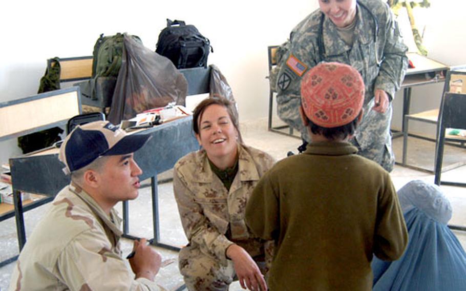 With the help of a translator, left, Canadian Army medic Sgt. Susan Paul, center, gives an Afghan boy some medicine and Capt. Darby Sivernail of the 10th Mountain Division, right, gives him some candy. The boy and his mother were visiting the doctors during a village medical outreach mission held by coalition forces.