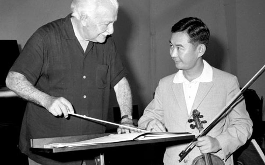 During a rehearsal with the Yomiuri Symphony Orchestra, Boston Pops conductor Arthur Fiedler chats with the orchestra's concert master, Takeshi Kobayashi.