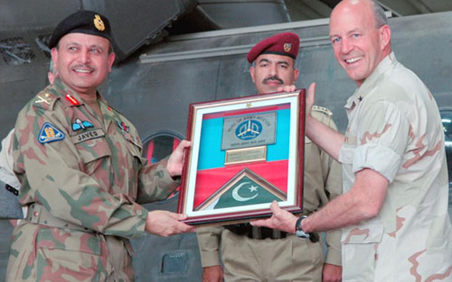 Maj. Gen. Javed Aslam Tahir, commander of Pakistani Army Aviation, accepts a plaque from Navy Rear Adm. Michael LeFever, commander of the Combined Disaster Assistance Center, Pakistan, during a ceremony Thursday marking the departure of American servicemembers from Pakistan.