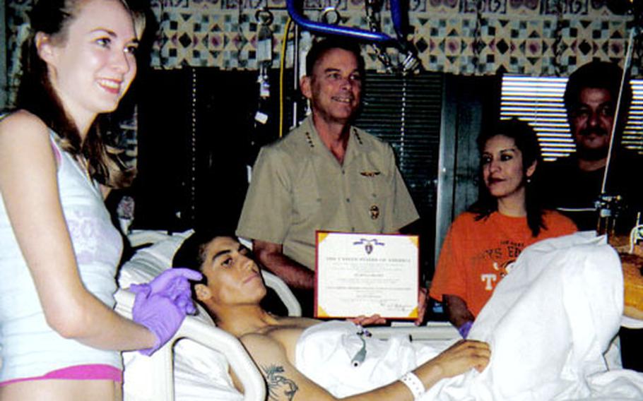 Lance Corporal Ben Gonzalez, center, receives a certificate for his Purple Heart from Gen. William “Spider” Nyland, Assistant Commandant of the Marine Corps, at the National Naval Medical Center in Bethesda, Md., about 10 days after he was injured. His wife Mindy, far left, and parents Diana and Denny Gonzalez look on.