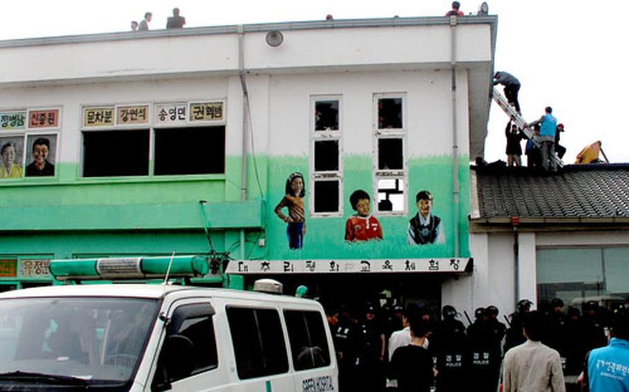 South Korean police Thursday lead off the last group of protesters from the roof of the former Daechu-ri Elementary School.