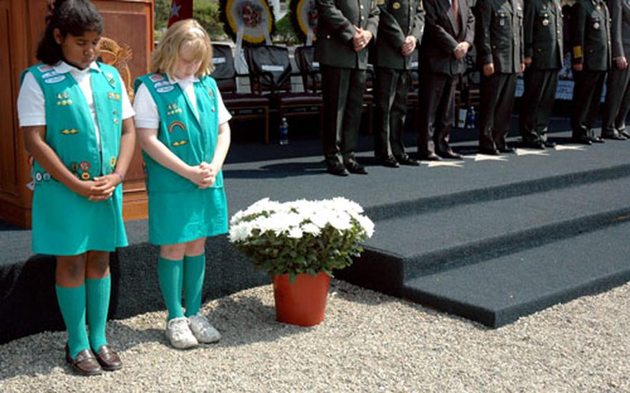 Breanne McIver, 11, left, and Elizabeth Kunde, 9, bow their heads Friday morning during a prayer at a Memorial Day service on Yongsan Garrison, South Korea. The service remembered all servicemembers killed, especially the 33,870 who died during the Korean War.