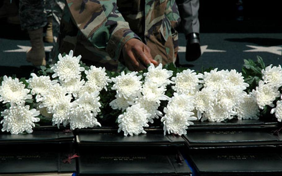 Servicemembers, veterans, family members and visitors place flowers atop tomes of the names of military members killed during the Korean War during a Memorial Day ceremony at Yongsan Garrison on Friday.