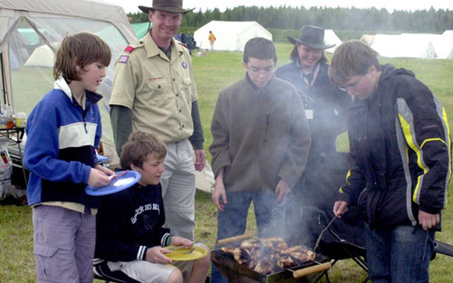 Dusseldorf Scouts, from left, Cameron Stewart, 11, Nikolas Baron, 14, Scout master Lt. Col. Mark Burtner, Chris Burtner, Intercamp chief Gayle Brown and Arthur Bondarev, 14, barbecue chicken at Vilseck Army Airfield on Sunday.