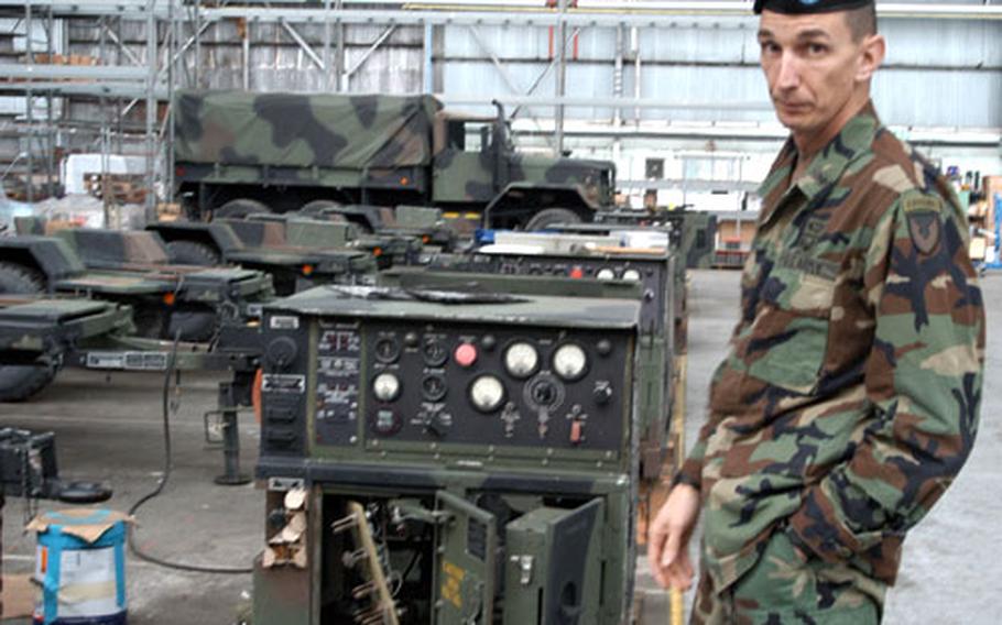 The U.S. Army Field Support Battalion-Hythe commander, Lt. Col. Martin Binder, stands next to a row of electric generators, just back from Afghanistan, that the staff is refurbishing.