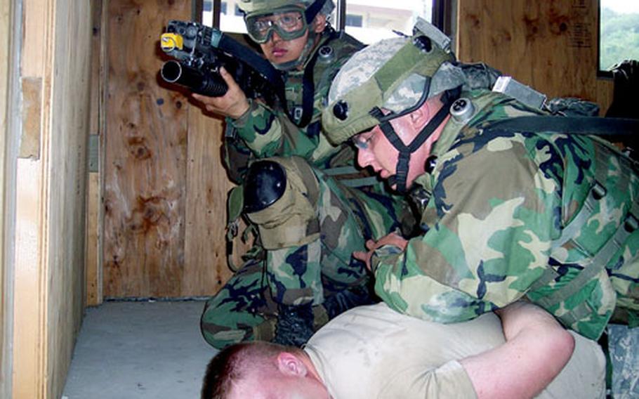 Pfc. Kris McWhirt subdues mock enemy combatant Spc. Jason Gearhart during 55th Military Police Company training at Rodriguez Range, South Korea, on Thursday.