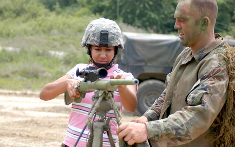 Tania Foster gets some weaponry instruction. Foster handed out gift certificates on May 31 to soldiers of the 2-9 sniper team.