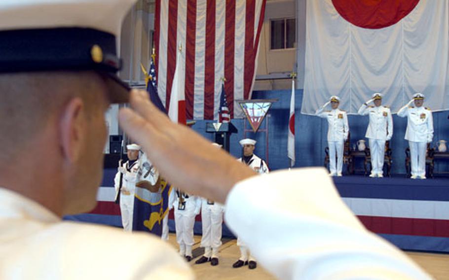 A sailor salutes at the change-of-command ceremony Wednesday for Naval Air Facility Misawa. On stage, from left, are Rear Adm. James Kelly Commander, U.S. Naval Forces Japan; Capt. R. Wayne Radloff, outgoing NAF Misawa commander; and new NAF Misawa Commander Capt. Peter B. Rush.