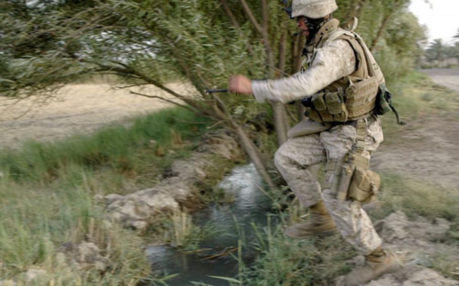 Marine Cpl. Samuel Ruppert, 22, of Ames, Iowa, takes a running leap over an irrigation ditch while patrolling farmland on the outskirts of Observation Post Omar in Iraq recently.