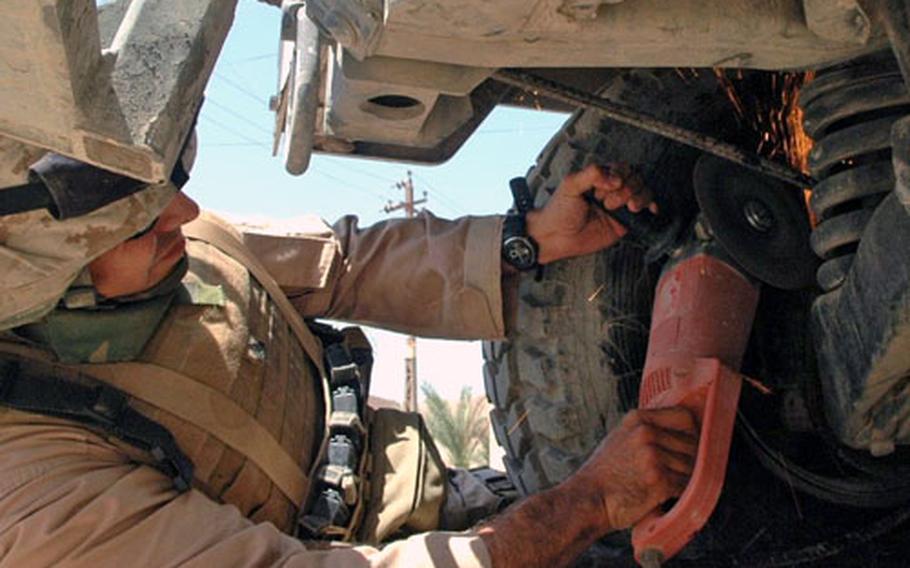 Marine Cpl. Brian Tomsovic uses a circular saw underneath a Humvee to cut off a length of rebar that had wrapped around the vehicle’s axle in Fallujah recently.