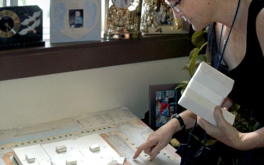 NEX General Manager Sandra Franklin looks over a model of the Navy Exchange store at Sasebo Naval Base. In her hand is a model of the former store that was demolished to make room for the new building.