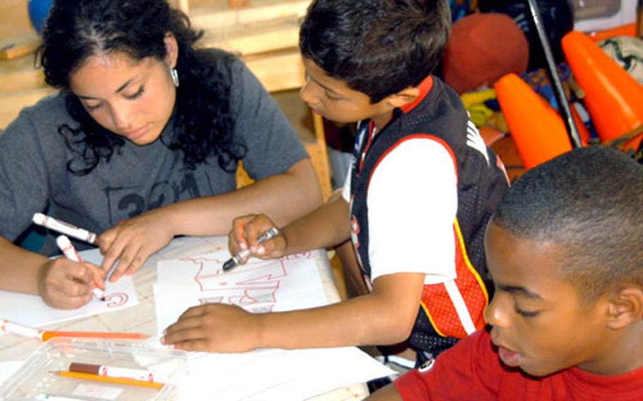 Stephanie Caicedo helps Bryan Hahlen, 8, center, and Decorio Perry, 9, during an arts and crafts session Thursday at Camp Adventure on Yokota Air Base, Japan.