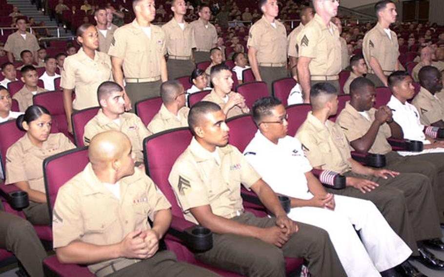 Marines and sailors stand as their countries of origin are called at the naturalization ceremony at Butler Theater on Camp Foster on Friday.