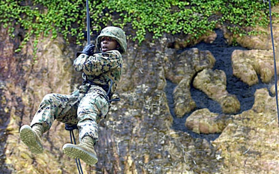 Lance Cpl. Ebony Rhodes, 21, from Houston, with 3rd Materiel Readiness Battalion on Camp Kinser, performs her first controlled break after stepping off the lip of the skid, a platform that simulates the back of a helicopter, at the rappel site on the Jungle Warfare Training Center Thursday.