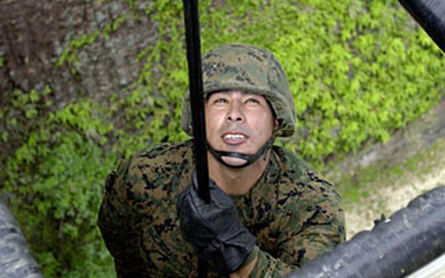 Sgt. Juan Rosas, 28, from Willcox, Ariz., with 3rd Transportation Support Battalion, looks up at an instructor before descending through a simulated hell hole — the opening near a helicopter’s fuselage — at the rappel site at the Jungle Warfare Training Center Thursday.