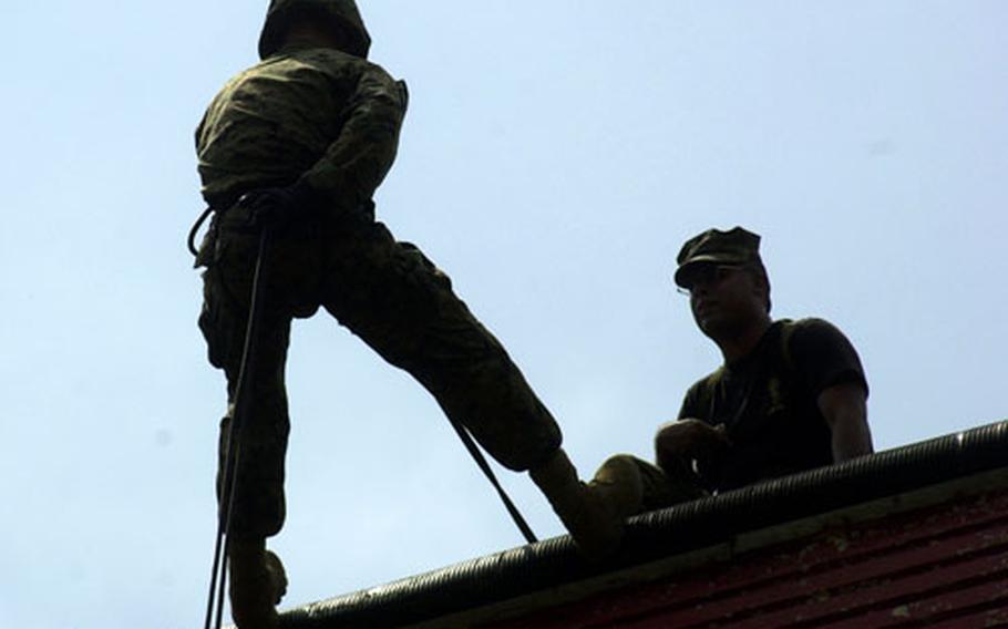 Lance Cpl. Louis Ocampo (left), 19, New York, with 3rd Materiel Readiness Battalion, moves into an L-shaped position against the wall as helicopter rope suspension training master Sgt. Benjamin Luna offers some final instructions at the rappel site at the Jungle Warfare Training Center Thursday.