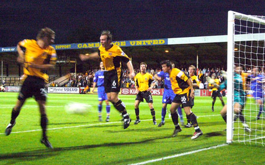 Cambridge defenders, in yellow and black, fend off an incoming corner kick from a visiting Exeter player in a recent game at Abbey Staduim in Cambridge. The home team lost the match 3-1.