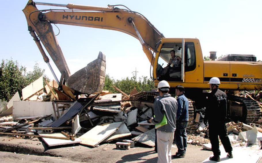 An earthmover demolishes a vacated home.