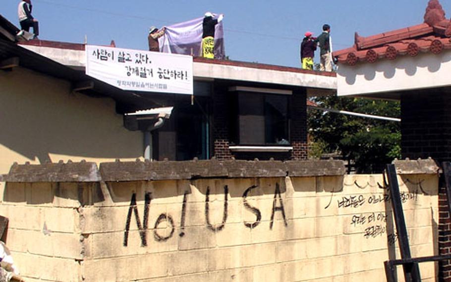 On the wall of a home in Daechu-ri, the words "No! USA" appear on a wall on Wednesday. Activists on the rooftop are shouting their opposition to the U.S.-South Korean agreement that will see Camp Humphreys expand onto nearby lands.