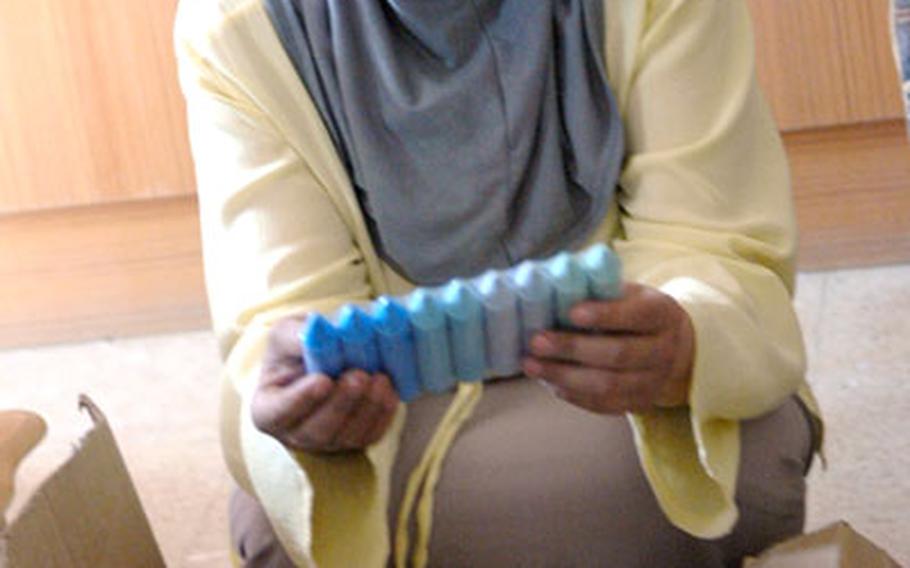 A teacher at Mohammed Bakr Sadr school in northern Baghdad sifts through boxes of donated school supplies Tuesday. Initially she was puzzled by the jumbo chalk; after several soldiers explained what it was, she broke into a wide smile and taught them how to say &#39;chalk&#39; in Arabic.