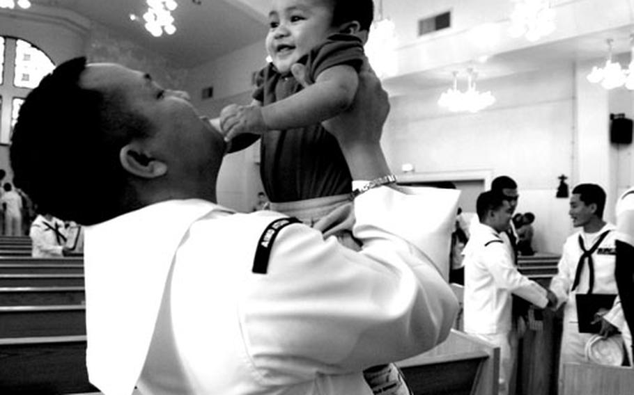 New American citizen Marc Patag, a petty officer 2nd class at Naval Air Facility Atsugi, Japan, hoists his six-month old son Marcus Gavin after Friday&#39;s naturalization ceremony.