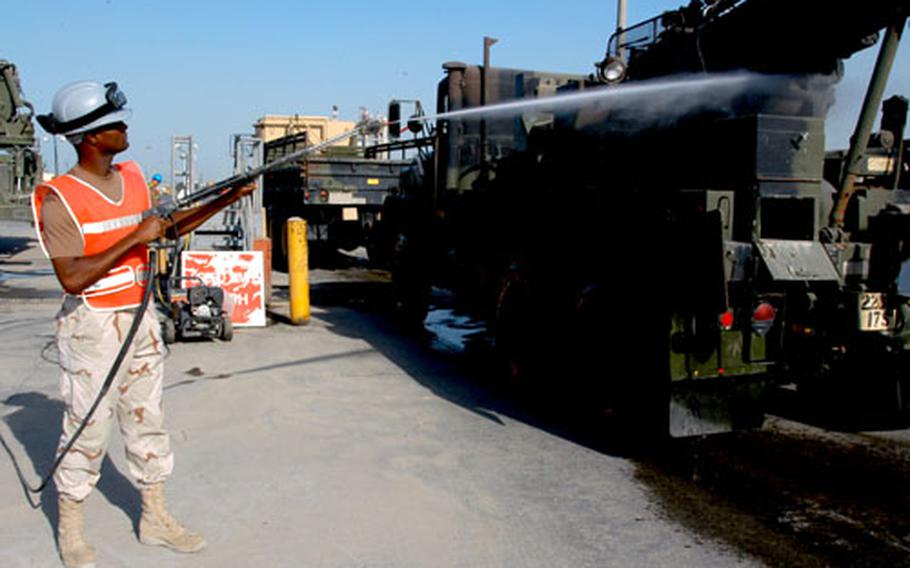 Petty Officer 2nd Class Cory Osburn, a rinse rack operator with Naval Expeditionary Logistics Support Group, sprays down a 5-ton truck at Kuwait’s Sea Port of Debarkation last week. The Naval Expeditionary Logistics Support Group controls the port’s marshalling yards and is responsible for giving equipment a final rinse before it’s loaded onto ships.