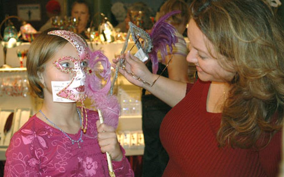 Nine-year-old Ellen Haapoja tries on an Italian mask as her mom, Jennifer Haapoja, looks on.