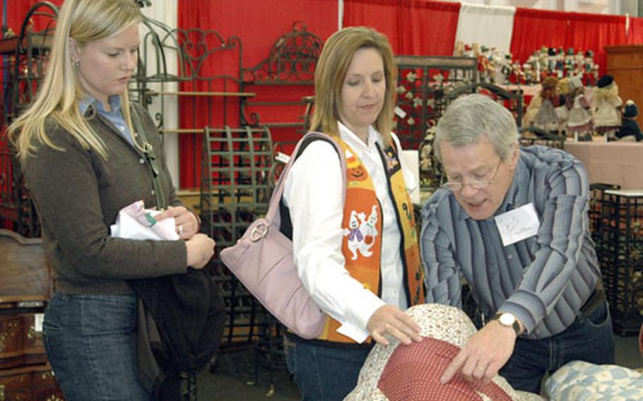 Michael Hammer points out the finer qualities of a handmade quilt to Darlene Guidry, center, and Cindy Dequevedo during the Heidelberg Community and Spouses Club Holiday Bazaar.