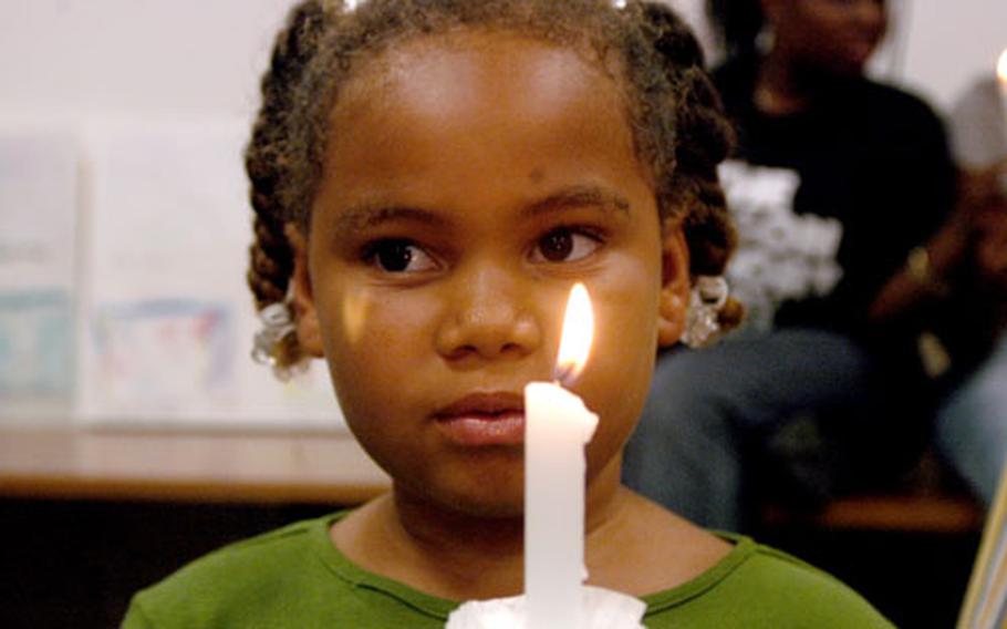 Ciana Eison, 7, holds a candle Tuesday evening during a vigil held to bring awareness to domestic violence. Naval Support Activity Naples, Italy, residents gathered for the observance at the community center.