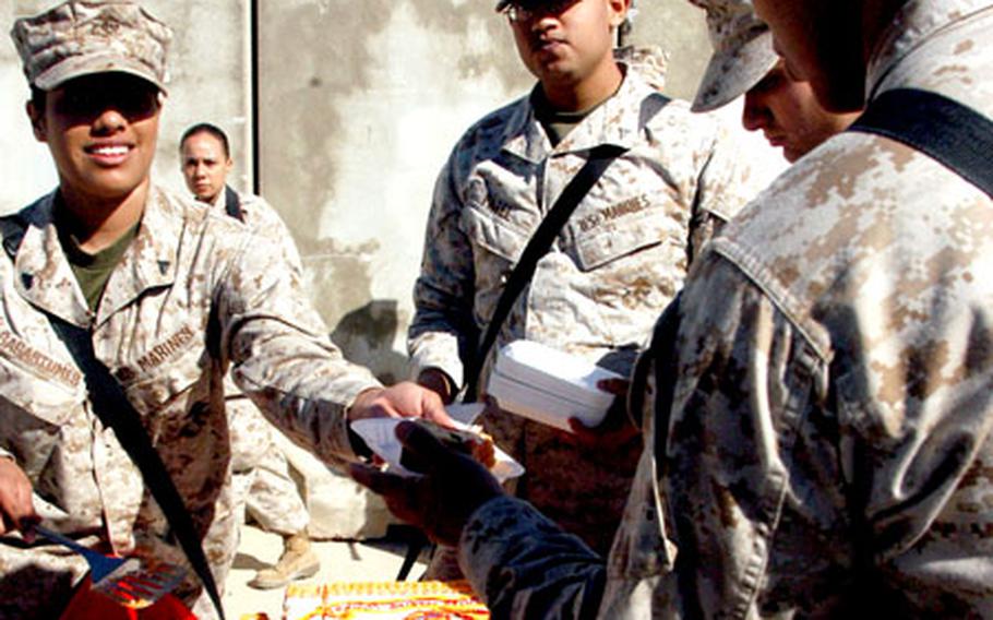 Cpl. Stephanie Sagastumes of Headquarters Company, 1st Marines Logistics Group, hands out cake Friday at Camp Taqaddum, Iraq, during the celebration of the 231st birthday of the U.S. Marine Corps.