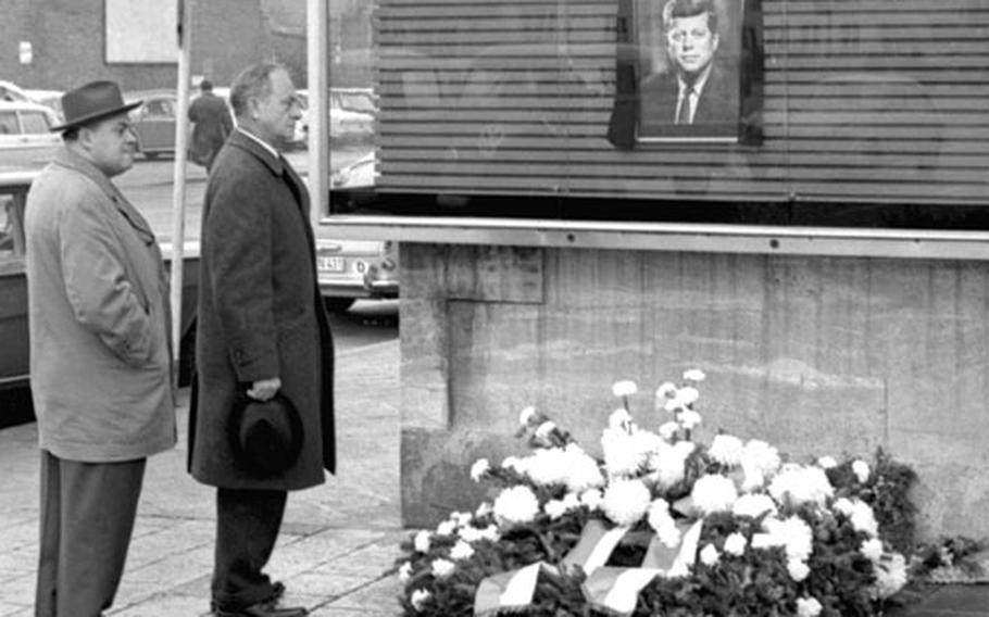 A large wreath placed by the city of Darmstadt, Germany, rests beneath a picture of President Kennedy at the city's Amerika Haus, which the city council renamed in honor of the fallen president.