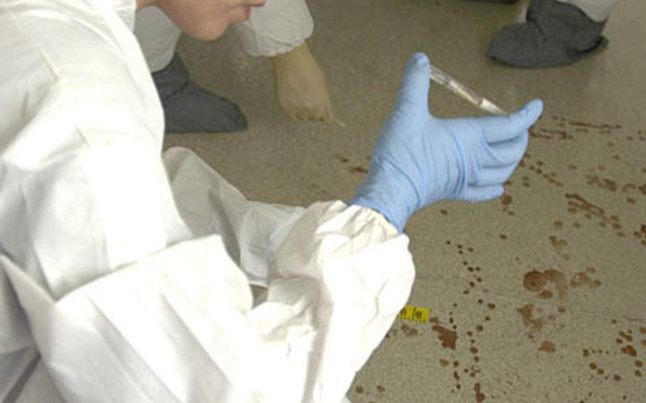 Sgt. Alma Fennell tests the stains on the floor of a vacant house in the Futenma housing area on Camp Foster during then advanced crime-scene training exercise.