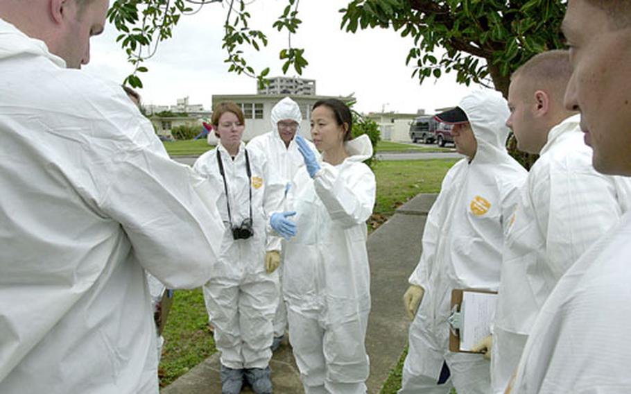 Special agent Elizabeth Toomer, center, with Naval Criminal Invistigative Service on Yokosuka Naval Base, Japan, and an instructor for advanced crime-scene investigation training, tells her students she wants them to examine the blood splatters in the empty house at Camp Foster, and then tell her what they think happened.