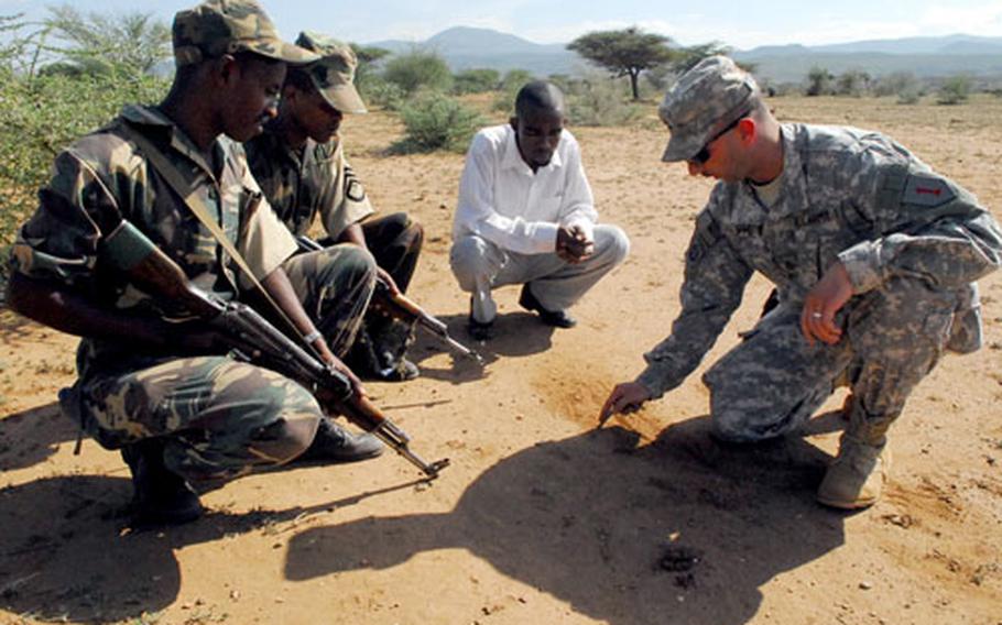 Military instructor and U.S. Army Sgt. First Class Bill Flippo, 27, of Winfield, Kan., illustrates a point by drawing in the sand while training Ethiopian army soldiers as a translator looks on.