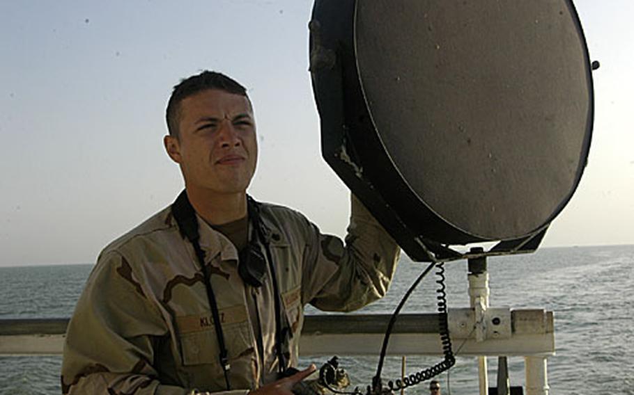 Petty Officer 2nd Class August Klotz, from the U.S. Coast Guard Cutter Wrangell, uses a loud-speaker warning system to warn a fishing trawler that sailed into a protective zone around the Iraqi Khawr al Amaya Oil Terminal in the Persian Gulf. The system contains several warning messages in Arabic.