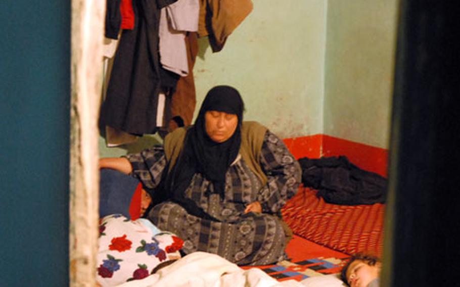 An Iraqi woman waits with her family as American soldiers search her house in Hawijah on Feb. 27.
