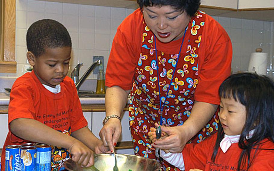(Left to right) Romel Anderson, 5, teacher&#39;s aid Jackie Powers and Lauren Lee, age 5, add food coloring to a bowl of scrambled eggs while preparing "Green Eggs and Ham" during "Read Across America Day" activities at Seoul American Elementary School, Friday.