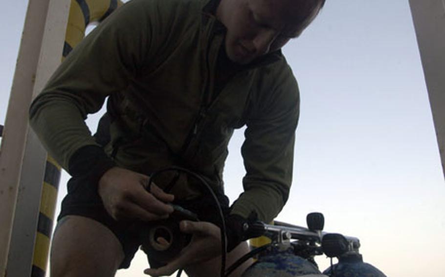 Petty Officer 2nd Class Brock Tetrick, 25, attaches a regulator to the oxygen tanks in preparation for a dive. The Navy divers of Mobile Diving and Salvage Unit 1, Detachment 3, based in Hickam Air Force Base in Hawaii, are deployed to the 5th Fleet area in the Middle East.