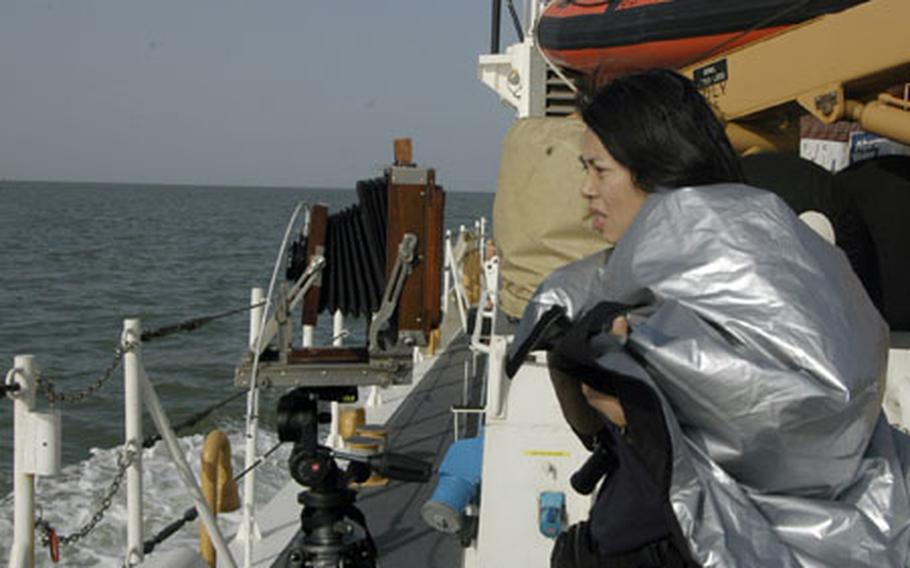 An-My Le, a photographer shooting sea-based operations and missions for her second book, sets up a Deardorff 5-by-7 large format camera.