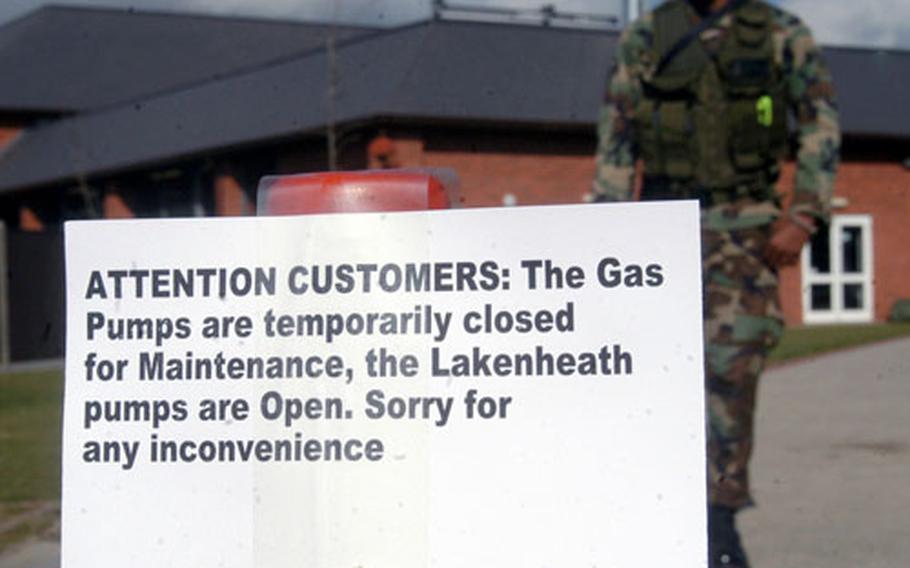 A security forces partrolman stands guard behind a traffic cone with a warning sign on it telling customers that RAF Mildenhall&#39;s gas station is closed.