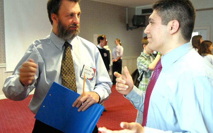 Gorden Videen, left, judge and keynote speaker at DODDS European Junior Science and Humanities Symposium, discusses Davide Chiericoni&#39;s poster presentation. Chiericoni, a Naples (Italy) High School student, was one of about 90 middle school and high school pupils attending the symposium.