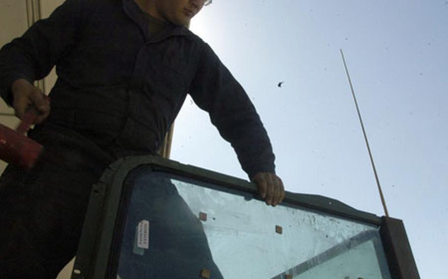 Lance Cpl. Joshua Carmack, 20, installs ballistic glass shielding on the turret of a Humvee.