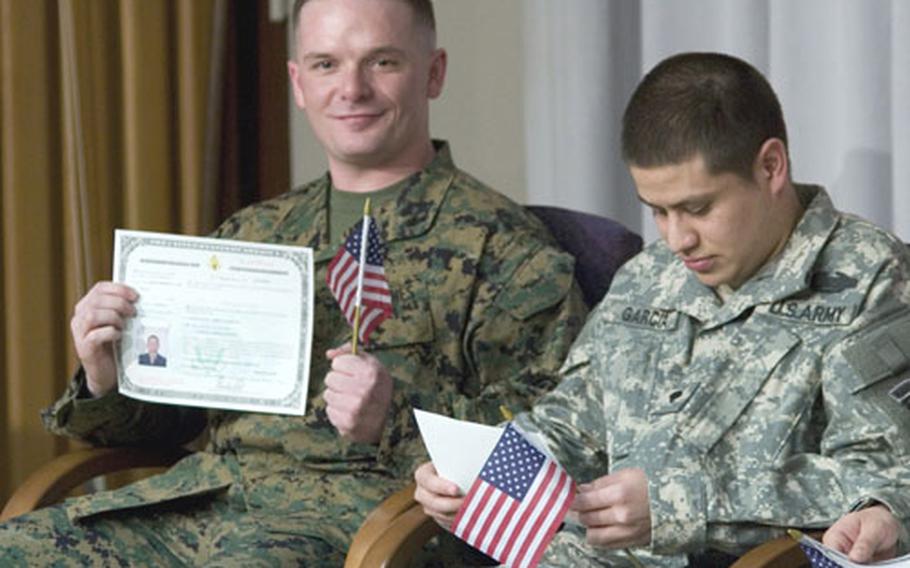 Lance Cpl. Carlos Lopes, left, a native of Portugal now with the U.S. Marine Corps&#39; 8th Engineer Support Battalion, proudly displays his citizenship certificate during a naturalization ceremony Monday at Walter Reed Army Medical Center in Washington. At right is Spc. Eduardo Garcia-Gonzalez, from Mexico, with the 502nd Infantry, 101st Airborne.