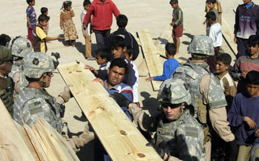 Soldiers of the 2nd Combined Arms Battalion, 136th Infantry Regiment of the Minnesota National Guard unload lumber in the village of al Angur. Some families will use the wood to burn for heat and cooking, while others will use it for construction projects.
