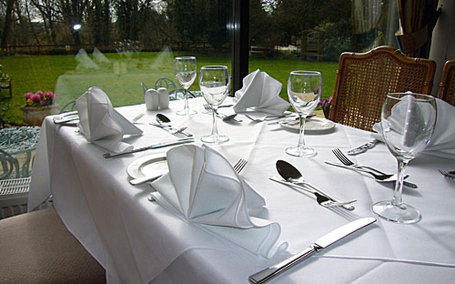 An attractive table setting is provided to those who dine at The Riverside Hotel&#39;s restaurant. A view of the hotel&#39;s grassy lawn and the River Lark is seen in the background.