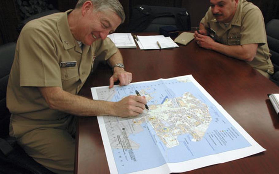 Commander, Naval Forces Japan, Rear Adm. James B. Kelly and CNFJ Command Master Chief Luis Cruz look over the Homeport Ashore initiative housing complexes on a map of the naval base on Yokosuka. Their goal is to have 95 percent of all fleet sailors living off the ships and in apartment style barracks.