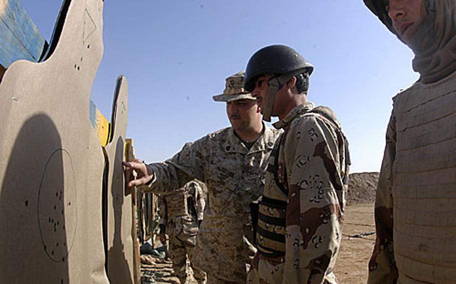 U.S. Marine Staff Sgt. Douglas Bisson counts the number of times Iraqi soldier Amir Khadum hit the center mass and head region on a target, praising the 23-year-old Iraqi soldier for his proficiency.