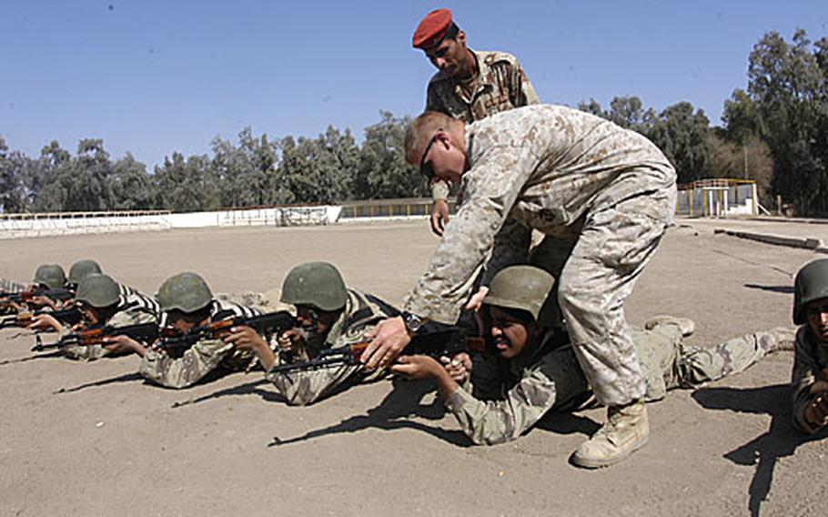 U.S. Marine Sgt. Christopher Woodard, 28, adjusts the aim of an Iraqi private while explaining to the Iraqi sergeant in the red cap how to make sure the recruits’ bodies are in proper alignment to hit a target.